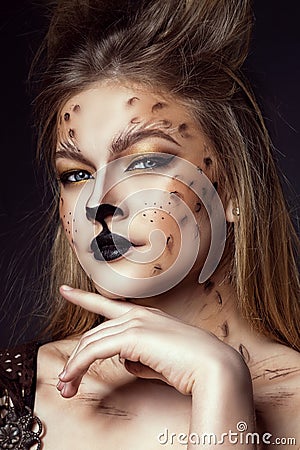 Close up portrait of young beautiful grey-eyed model with artistic leopard make-up and brushed up hair looking straight Stock Photo