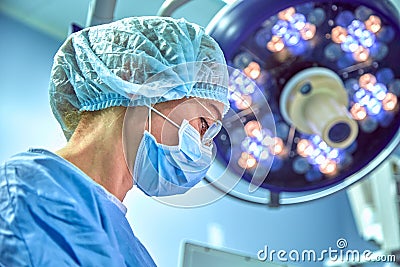 Close up portrait of young female surgeon doctor wearing protective mask and hat during the operation. Healthcare Stock Photo
