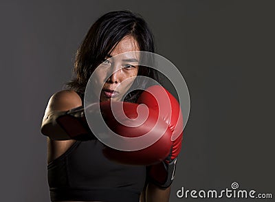 Close up portrait of young fit Asian Chinese woman in fitness top and boxing gloves throwing punch in bad girl attitude angry and Stock Photo