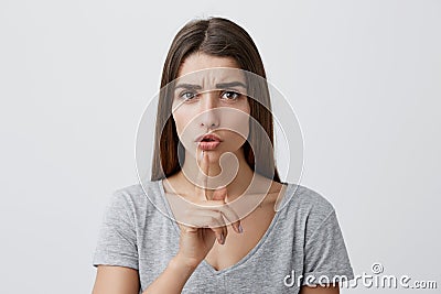 Close up portrait of young handsome brunette caucasian woman with long hair in gray t-shirt holding index finger in Stock Photo