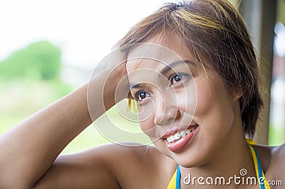 Close up portrait of young happy beautiful Asian woman from Indonesia looking thoughtful and pensive daydreaming and thinking Stock Photo