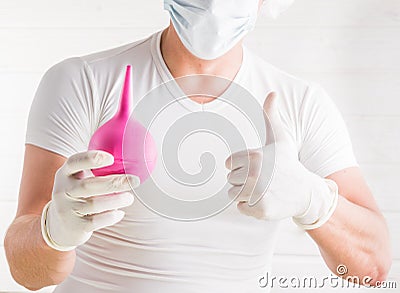 Close up portrait of a young male doctor with stethoscope dressed in uniform pointing finger at enema and looking at camera isolat Stock Photo