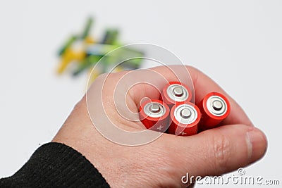 Red colours of batteries in hand on a white background. Close up of positive ends batteries, selective focus. Used battery for Stock Photo