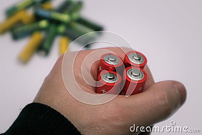 Red colours of batteries in hand on a white background. Close up of positive ends batteries, selective focus. Used battery for Stock Photo