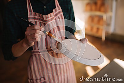 Close up of potter`s hands making ornament on ceramic product. Plate in male`s hands. Young artist Stock Photo