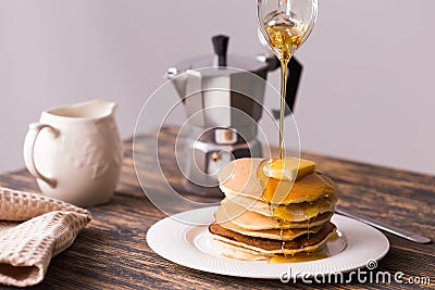 Close-up of pouring maple syrup on stack of pancakes. Stock Photo