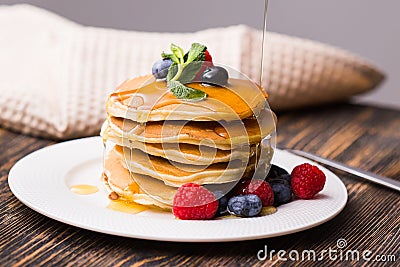 Close-up of pouring maple syrup on stack of pancakes. Stock Photo