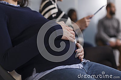 Close up of pregnant job recruiter holding hand on belly bump Stock Photo
