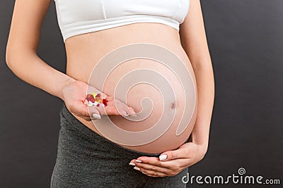 Close up of pregnant woman holding a pile of pills at colorful background with copy space. Taking medications and vitamins during Stock Photo