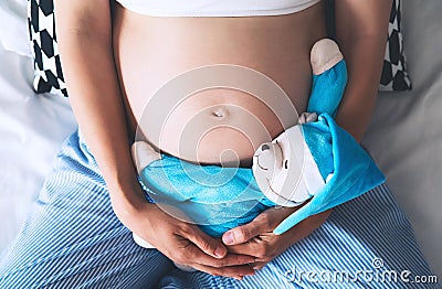 Close-up pregnant woman`s belly with teddy toy bear. Stock Photo