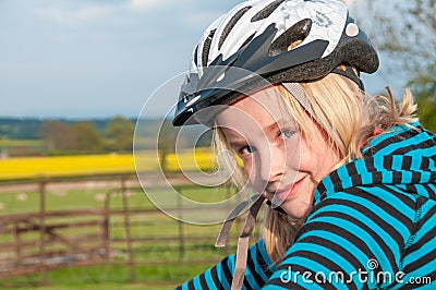 Close up of a pretty young blonde girl wearing a cycle helmet in a rural setting Stock Photo