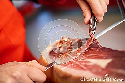 Professional cutter carving slices from a whole bone-in serrano Stock Photo