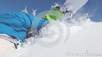 CLOSE UP: Professional snowboarder trips and falls flat on his face into snow. Stock Photo