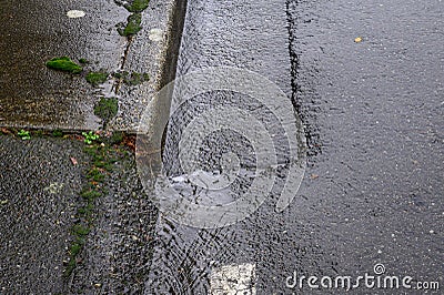 Close up of rainwater running down the edge of the street and sidewalk Stock Photo
