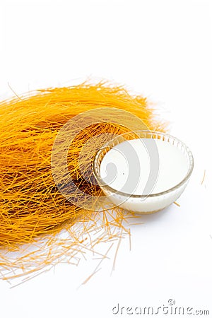 Close up of Raw vermicelli or sevee or seviyan or seviyaan and dry fruits isolated on white with a bowl of milk used to make kheer Stock Photo