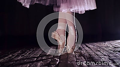 close up, in rays of spotlight, on stage of old theater hall. ballerina in white skirt, raises on toes in pointe Stock Photo