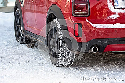 Close up rear view of a red car on parking,, dirty rear wheel tire on snow Stock Photo