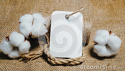 Close up rectangle paper tag with rope on vintage fabrics beside cottons balls. Mock up cotton template Stock Photo