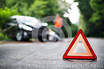 A close up of a red emergency triangle on the road in front of a car after an accident. Stock Photo