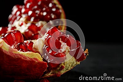 A close-up of a red garnet. A bittersweet pomegranate on a black background. A pomegranate full of juicy, fres Stock Photo