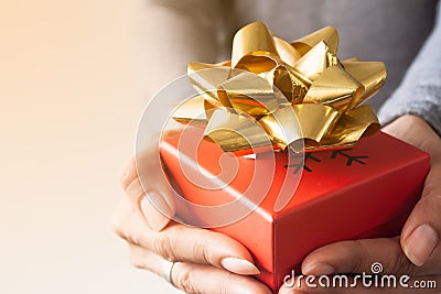Close up red gift box with gold colour ribbon on woman hands Stock Photo