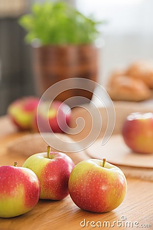 Close-up on red and green apples on wooden table in dining room interior with healthy food. Real photo Stock Photo
