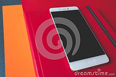 Close up of red leather covers of a mobile phone and a notebook with Agenda written on the cover Stock Photo