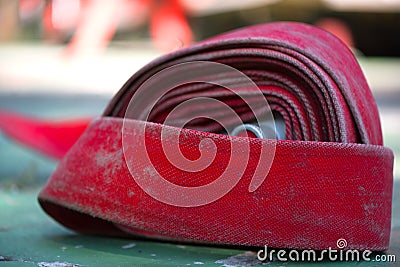 Close up of red rolled up fire extinguishing hose with coupling and nozzle, Red old Fire Hose texture on the floor, Firefighters Stock Photo