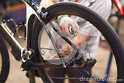 Close up of repairman is holding spray lubricant in his hand to lubricate the bike chain Stock Photo