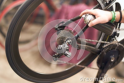 Close up of repairman is holding spray lubricant in his hand to lubricate the bike chain Stock Photo