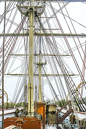 Close-up of the rigging of a wooden tall sail ship with a shiny wet wood deck against overcast sky Stock Photo