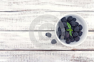 Close up of ripe blackberries in a white ceramic bowl over rustic wooden background Stock Photo