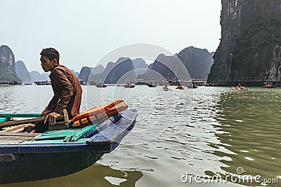 Close up rowing boats man sit in the boat that floating on emerald water with limestone islands in background in summer. Editorial Stock Photo