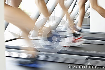 Close Up Of 3 Runners Feet On Running Machine In Gym Stock Photo