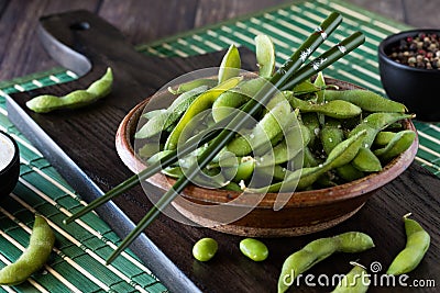 Close up of a rustic bowl of edamame beans in the shell with chopsticks on top. Stock Photo