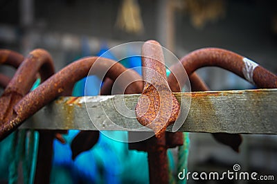 Close up of a rusty grappling hook, hanging on a wooden beam Stock Photo