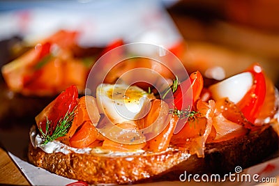 Close up of salmon toast starter or appetizer with egg and tomato on sun light. Bread slice with salted smoked salmon Stock Photo
