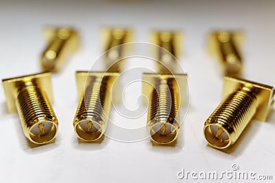 Close-up of scattered gold plated SMA male connectors electronics components in partial focus on white background Stock Photo