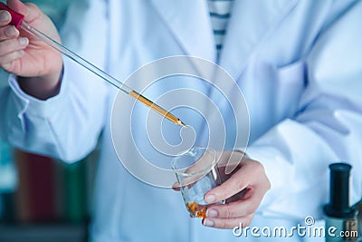 Close up scientist hand pouring orange liquid Stock Photo