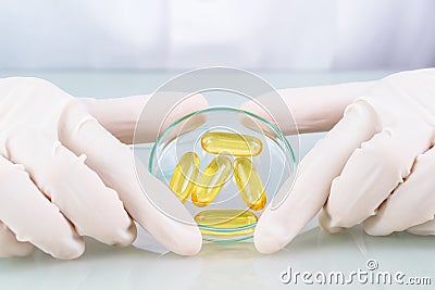 Close up Scientist holding Omega 3 capsule in labcoat Stock Photo