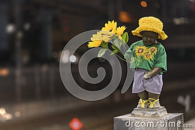 Close-up sculpture of a little boy Manneken pee peeing and holding sunflower flowers on the quay of hamamatsucho station in Tokyo Stock Photo