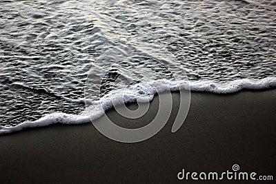 Sea foam on black sand Stock Photo