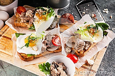 Close-up Sea food sandwich. Cod liver, fresh lettuce, pea sprouts, tomatoes and fried eggs. Healty and tasty breakfast on a Stock Photo