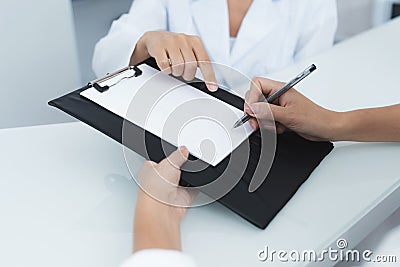 Close up. The secretary in a medical clinic helps the patient complete the necessary forms before starting treatment. Stock Photo