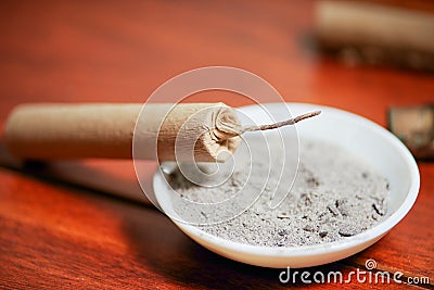 Close up of selective focus of brown firecrackers close to a white bowl with gunpowder, over a wooden table Stock Photo