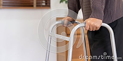 Close up of senior man with disability leaning on walker to move along the room Stock Photo