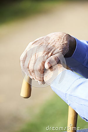 Close Up Of Senior Man's Hands Resting On Walking Stick Stock Photo