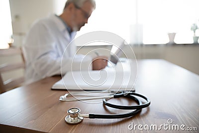 Close up senior mature doctor work desk with stethoscope Stock Photo