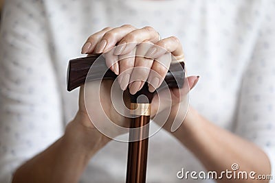 Close up mature woman holding hands on walking stick, cane Stock Photo