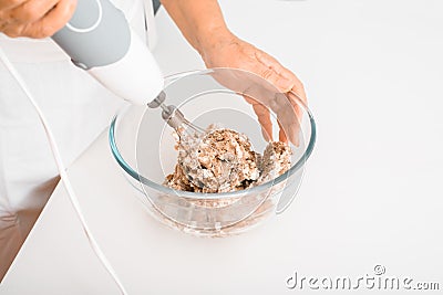 Close-up of senior woman's hand preparing cream pie filling, housewife whipping ingredients using blender mixer indoors Stock Photo